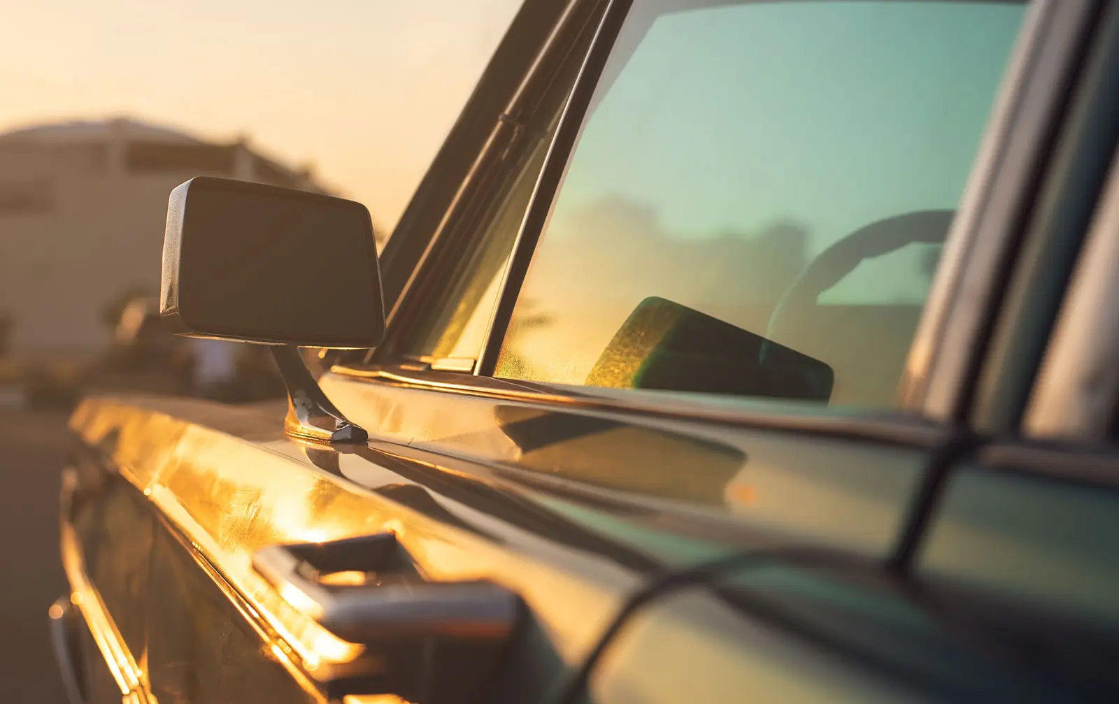 Low evening sun on a car&rsquo;s side window and door mirror